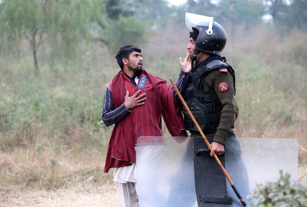 A demonstrator detained by a policeman gestures near the Faizabad junction in Islamabad